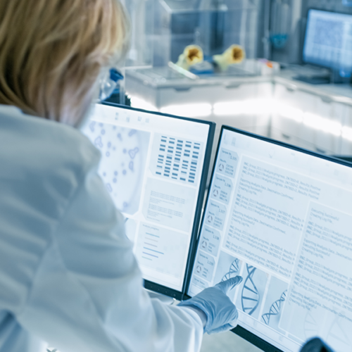 Clinical researcher pointing to a monitor displaying biomedical data.