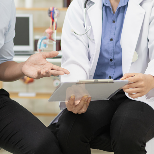 Two individuals meeting over a clipboard. One individual is dressed like a clinician.