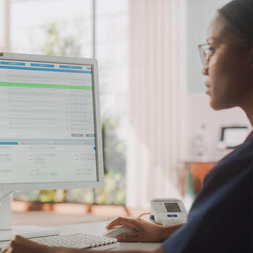 A healthcare professional reviews an electronic health record on a monitor.