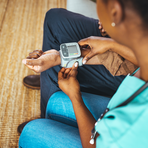 A healthcare worker measures an elderly man's blood pressure in his home.