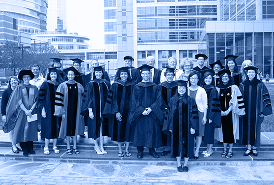 A group of GGEB graduates and faculty pose in caps and gowns.