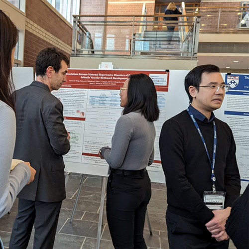 DBEI faculty, researchers, and students converse in front of research posters.