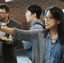 Sherry Xie points at a research poster.